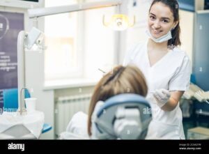 hymyileva hammaslaakari hoitamassa potilaan hampaita