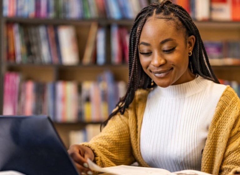 nuori opiskelija lukee lainahakemusta kirjastossa